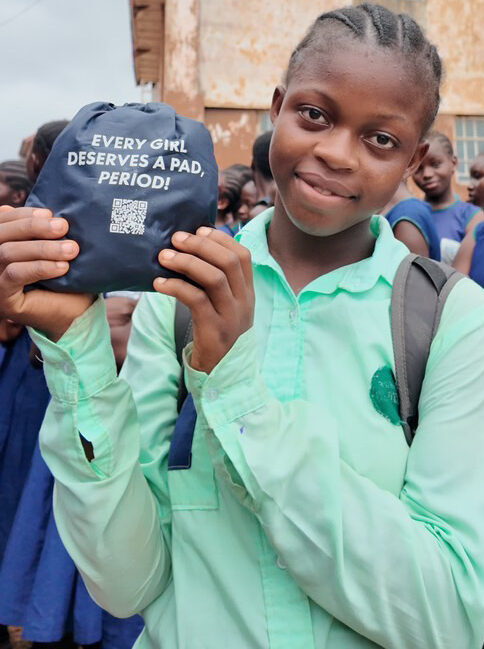 En pige i FANT Sierra Leones fællesskaber viser sit genanvendelige bind fra SheforShe pads, som er blevet doneret af OBT Shipping Group